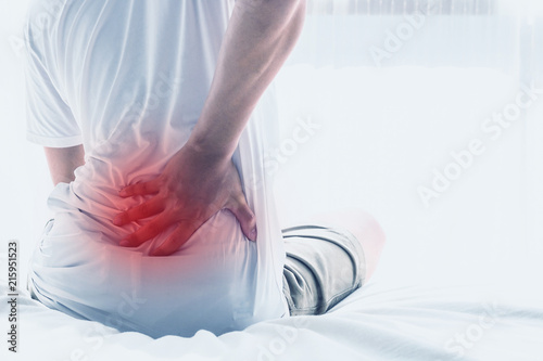 Asian man back pain and sit on bed in bedroom in the morning.color tone