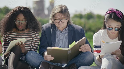 Professor reading a textbook to students in the park. photo