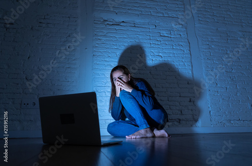 Картината върху платно Sad and scared female Young woman with computer laptop suffering cyberbullying and harassment being online abused by stalker or gossip feeling desperate and humiliated in cyber bullying concept