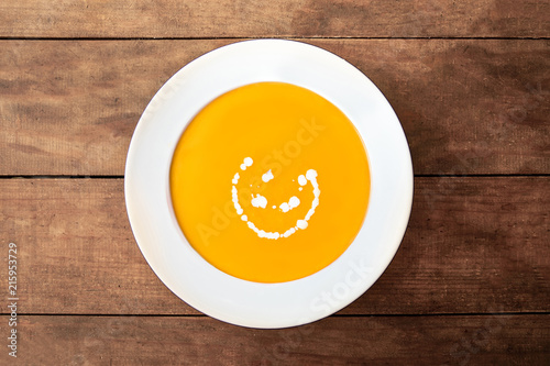  Squash Soup. Fresh homemade cream of Carrot and Pumpkin  soup with a swirl of cream  on dark wooden table. Top view