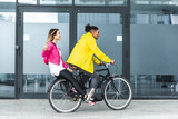side view of happy multicultural couple riding on bicycle at city street