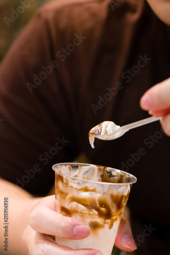 close up eat out vanilla ice cream with chocolate fudge in cup.hands man eating ice cream vanilla with chocolate fudge on top.tasty sweets vanilla ice cream and chocolate fudge in fast food.