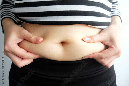 woman hand catching fat body belly paunch , diabetic risk factor .