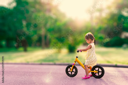 Fototapeta Naklejka Na Ścianę i Meble -  Little girl learns to riding balance bike in the park