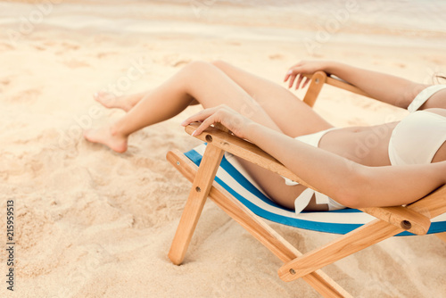 cropped view of woman relaxing on beach chair on sand