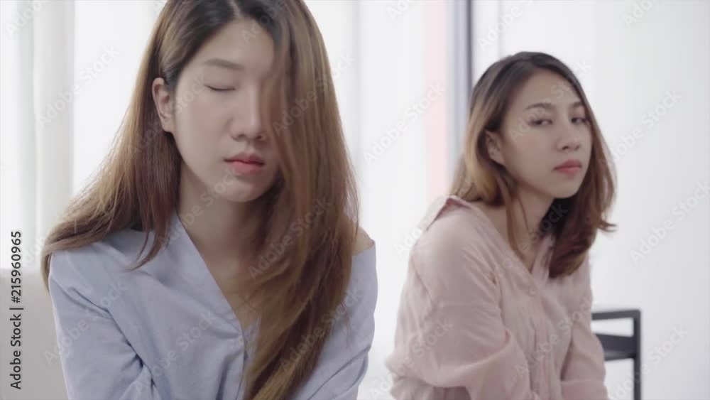 Unhappy Asian lesbian lgbt couple sitting each side of sofa with moody emotion in living room. Women conflict with her girlfriend and have bad relationship at home. Unhappy Asian lesbian lgbt couple sitting each side of sofa with moody emotion in living room. Women conflict with her girlfriend and have bad relationship at home.