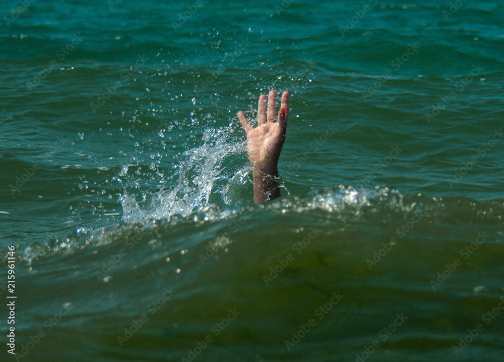 A girl drowning in the sea. Hand over water asking for help.