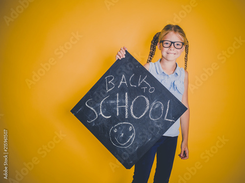 beautiful blond girl with glasses holding blackboard with the words back to school on it photo