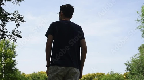 Hombre de espaldas a contraluz bajo un cielo azul despejado al aire libre en la naturaleza.