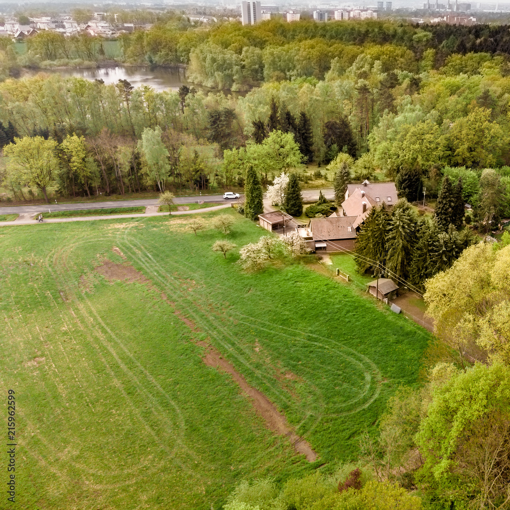  Aerial view of a house on the edge of a forest in front of a meadow behind a road
