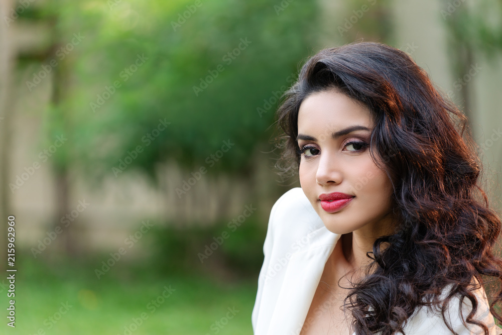 Naklejka premium Side view portrait of attractive young asian brunette woman looking at camera smiling with confident lifestyle concept. Gorgeous look of young indian businesswoman with perfect makeup and copy space.