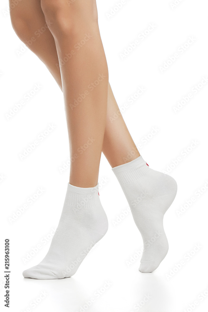 Cropped side view of beautiful female legs in white socks, isolated against  a white background. The young woman walking on her tip-toes. Comfortable  legwear for ladies and girls. Cozy women's hosiery. Stock