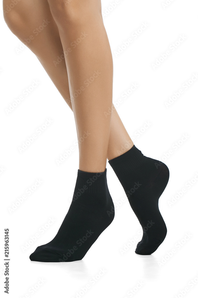 Cropped side view of beautiful female legs in black socks, isolated against  a white background. The young woman walking on her tip-toes. Comfortable  legwear for ladies and girls. Cozy women's hosiery. Stock-Foto