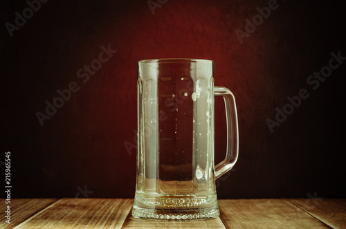 empty a glass from beer on a red light background/empty a glass from beer on a wooden table and a red background, selective focus
