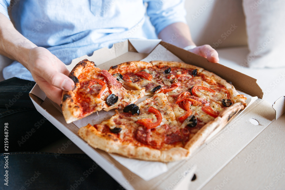 Close up of a pizza in box on men's lap