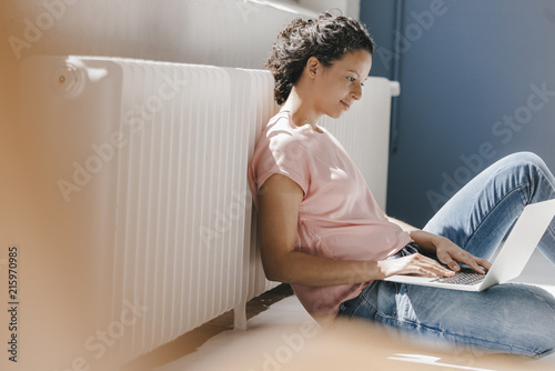 Woman sitting on ground, using laptop