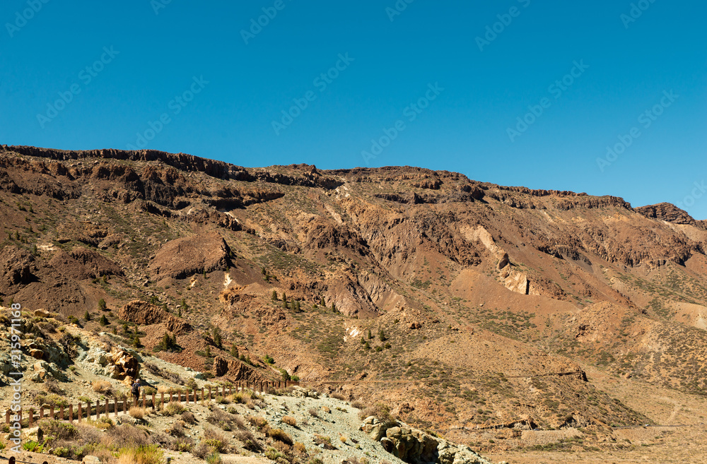View of landscape of Teide National Park on Tenerife, Canarias islands, Spain. Yellow and black sand and distance view of mountains roads and volcano. View of landscape of Teide National Park on Tenerife, Canarias islands, Spain. Yellow and black sand and distance view of mountains roads and volcano.