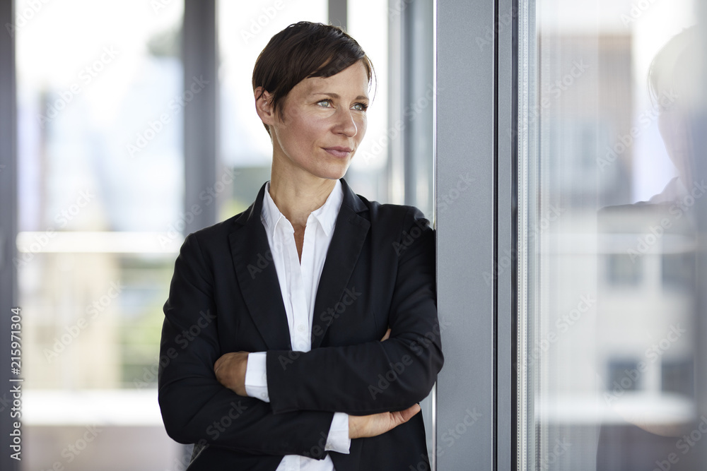 Businesswoman in office looking out of window Businesswoman in office looking out of window