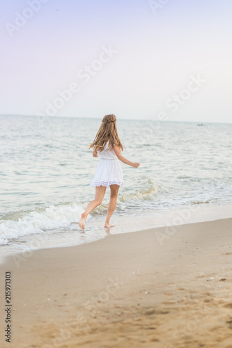 A beautiful model in a white dress is sexually running around on the beach on a beach