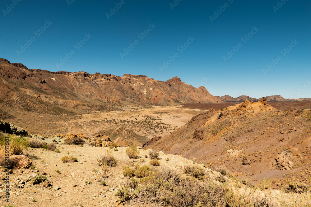 View of landscape of Teide National Park on Tenerife, Canarias islands, Spain. Yellow and black sand and distance view of mountains roads and volcano.