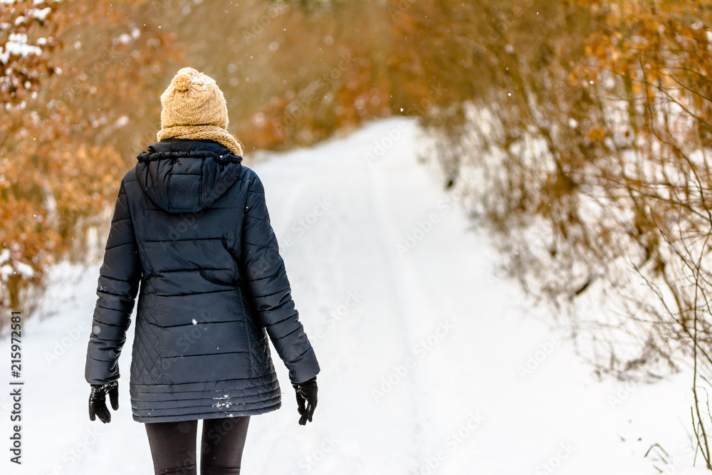 Woman walking in snow in winter clothes. Girl on snowy road in park. Woman walking in snow in winter clothes. Girl on snowy road in park.