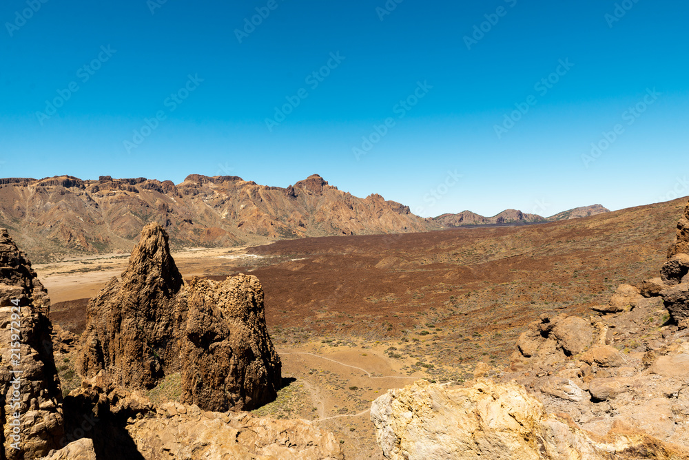 View of landscape of Teide National Park on Tenerife, Canarias islands, Spain. Yellow and black sand and distance view of mountains roads and volcano. View of landscape of Teide National Park on Tenerife, Canarias islands, Spain. Yellow and black sand and distance view of mountains roads and volcano.