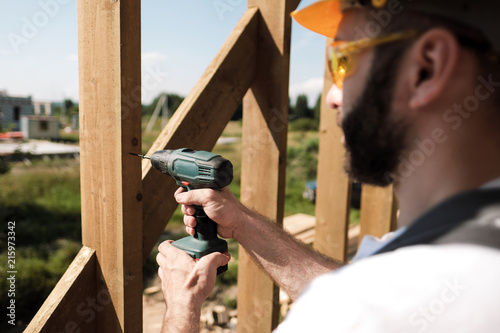 The man is a builder on the roof of a wooden frame house. photo