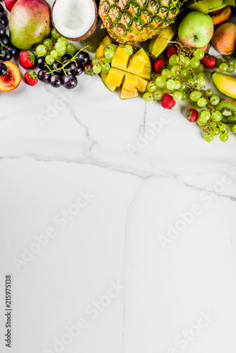 Various tropic fruits, summer vitamins concept, coconut, pineapple, grapes, peach, nectarine, strawberry, apples, mango, banana. top view copy space
