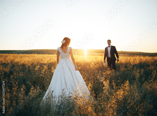 Young couple walking in the wheat field at sunset