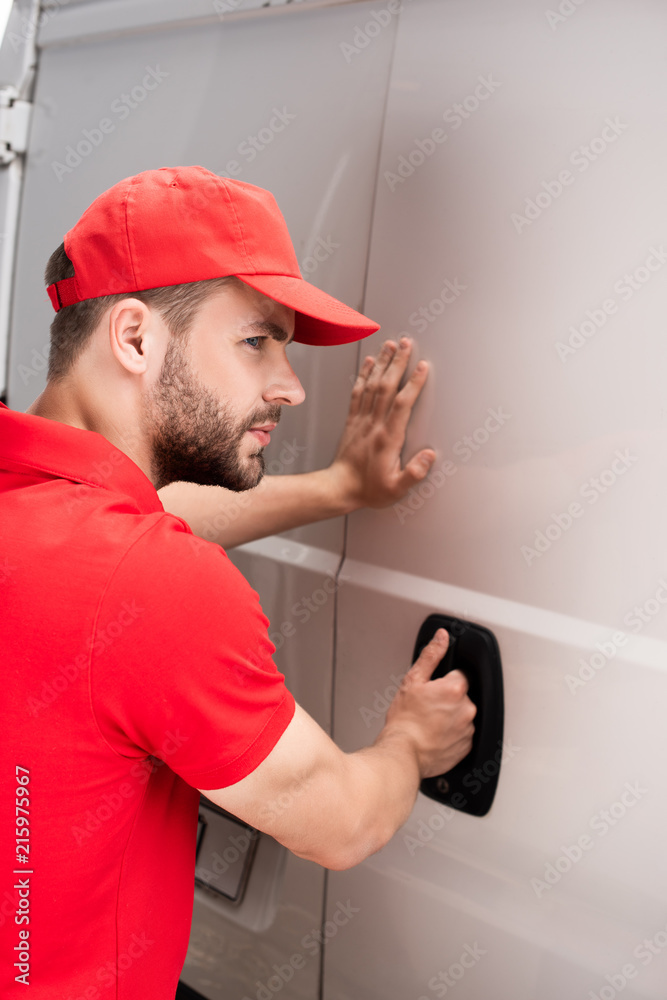 side view of young delivery man opening van door