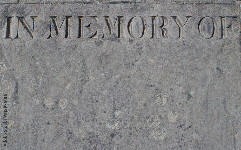 A weathered memorial stone engraved with the words - in memory of - with space below for text. A weathered memorial stone engraved with the words - in memory of - with space below for text.