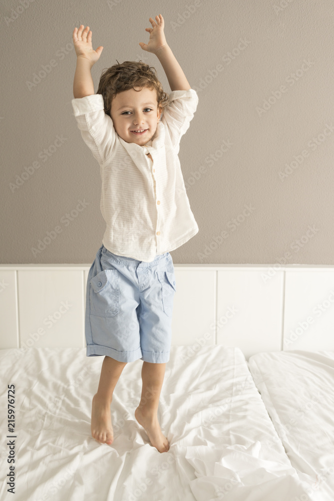 Child standing on top of a bed.