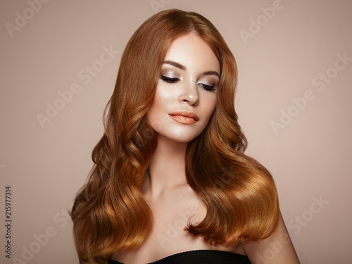 Redhead Girl with Long Healthy and Shiny Curly Hair. Care and Beauty. Beautiful Model Woman with Wavy Hairstyle. Make-Up and Black Dress