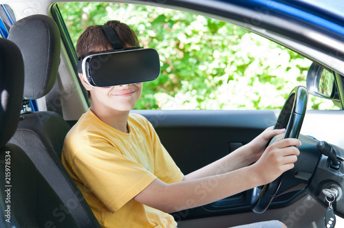 A teenager in virtual reality glasses, driving a car.