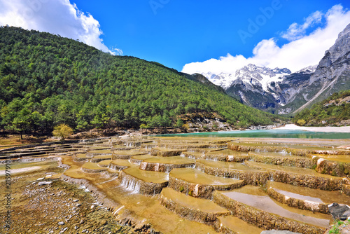 Baishuihe waterfall in front of Yulong or Jade Dragon Snow Mountain in the background, Lijiang, China photo