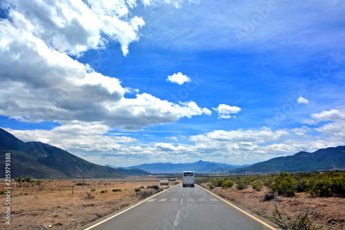Road in the middle of natural mountain landscape with a van and car on the road with blue sky background