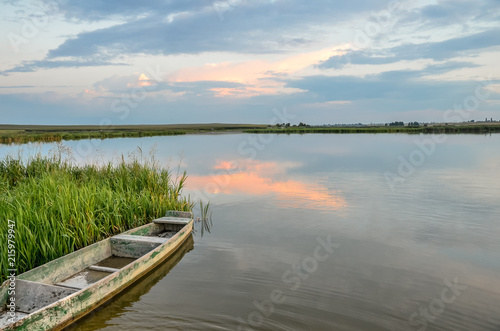 Breathtaking summer scenery with old wooden boat in warm evening sunlight.