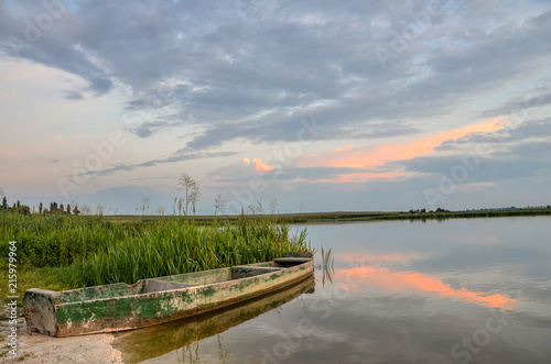 Fototapeta Naklejka Na Ścianę i Meble -  Breathtaking summer scenery with old wooden boat in warm evening sunlight.