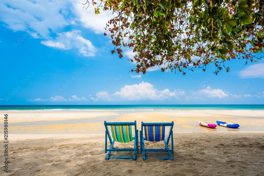 Tropical tree and beach chair at white sand beach and blue sea