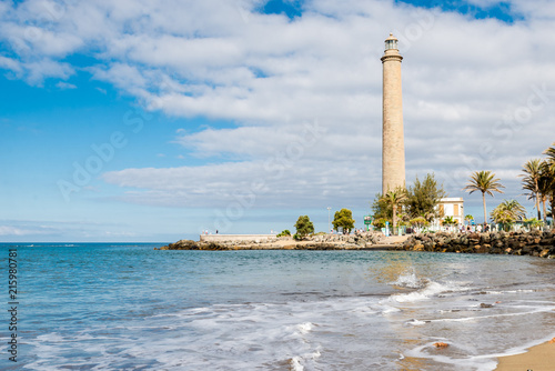 Tenerife, Canarias islands/ Spain - July 22, 2018: View of empty beach of tourists and high lighthouse on Canarias, view of bay with palms. Blue Atlantic ocean and beach on Gran Canaria. photo