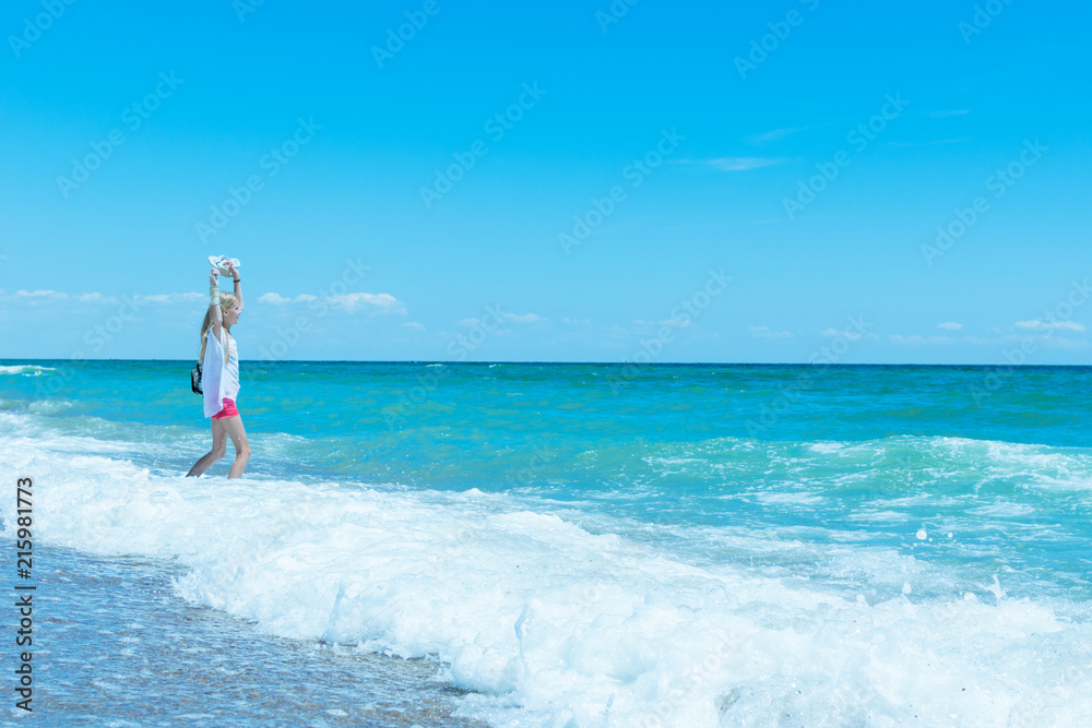 A teenage girl goes in the water at the sea, the ocean. The concept of rest, freedom, vacations.