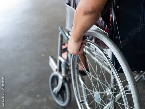 Fototapeta Naklejka Na Ścianę i Meble -  A disabled man is sitting in a wheelchair. He holds his hands on the wheel. Handicap people Concept.