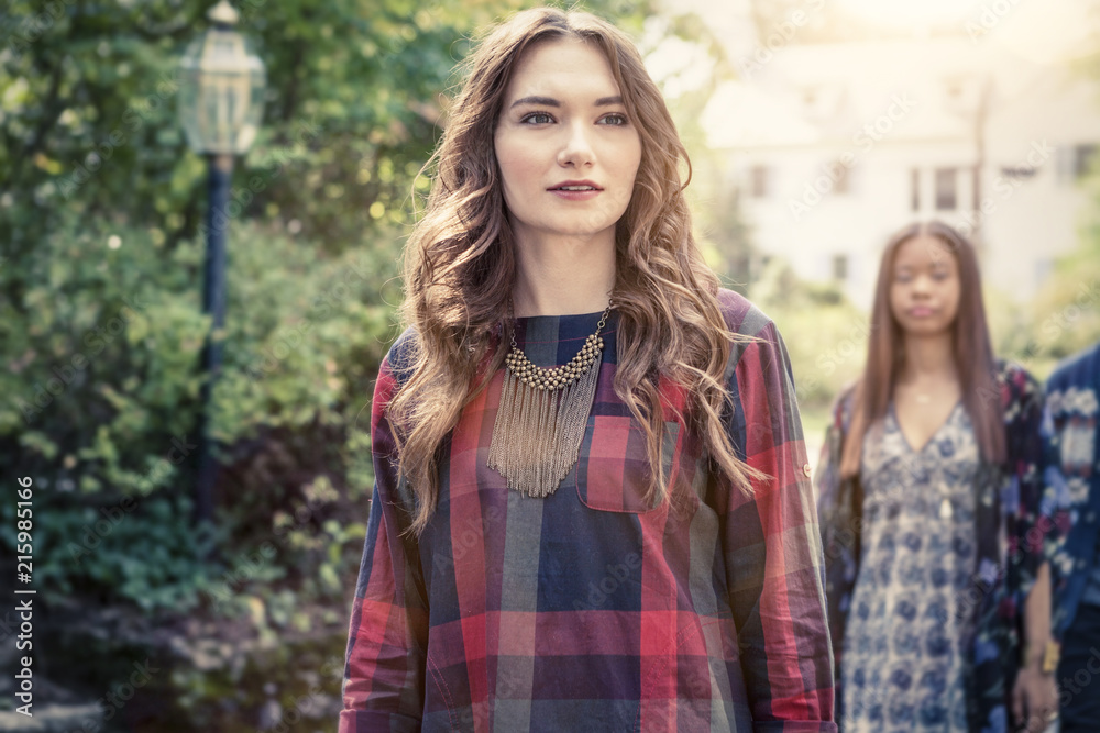 Young woman walking outdoors with people in background Young woman walking outdoors with people in background