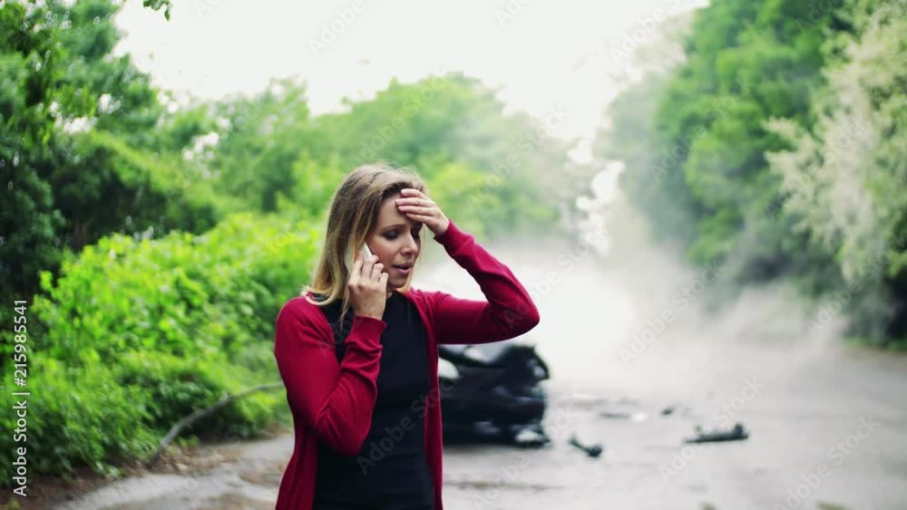 Young woman making a phone call after a car accident, smoke in the background. Young woman making a phone call after a car accident, smoke in the background.