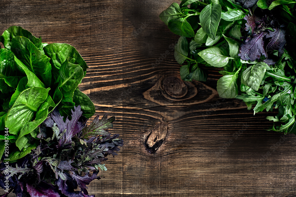 Variety of fresh organic herbs on wooden background. Freshly harvested herbs including basil, arugula. Top view. Copy space.