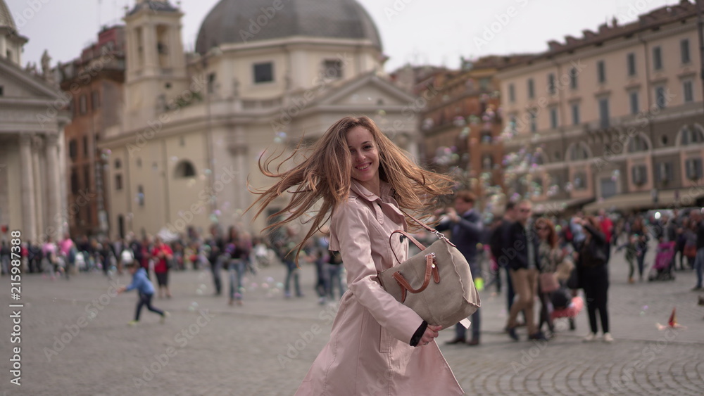 Pretty girl in Rome, Italy. Young lady dancing in the ancient Roman centre on the background of famous buildings. Italian square full of people