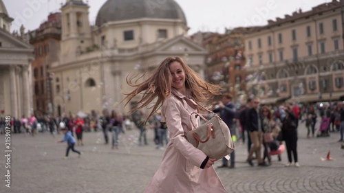Pretty girl in Rome, Italy. Young lady dancing in the ancient Roman centre on the background of famous buildings. Italian square full of people © Maryana
