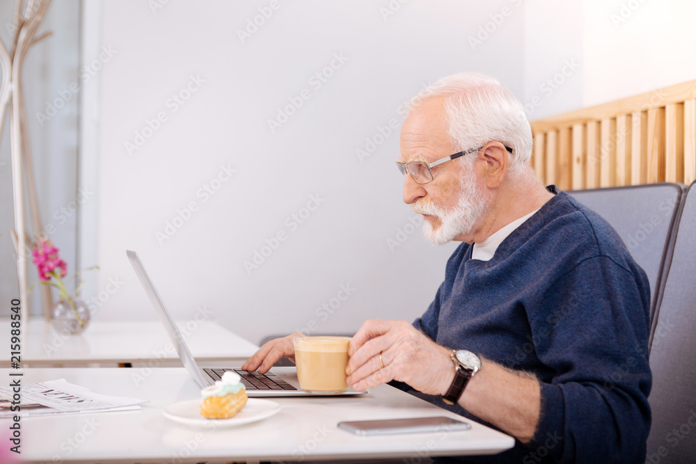 Surf Internet. Bussing senior freelancer using laptop and posing in profile Surf Internet. Bussing senior freelancer using laptop and posing in profile
