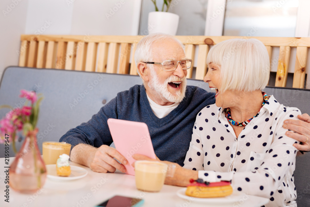 Funny video. Cheerful senior couple applying tablet and laughing Funny video. Cheerful senior couple applying tablet and laughing
