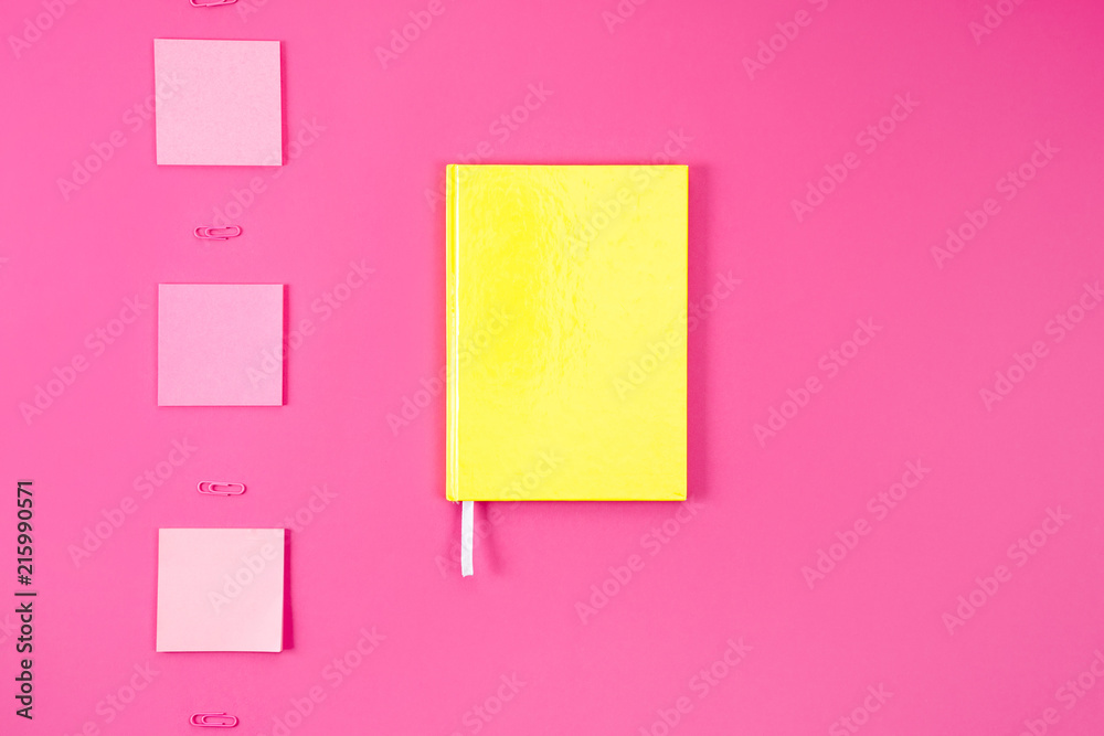 flat lay with yellow notebook with stickers and paper clips on pink flat lay with yellow notebook with stickers and paper clips on pink